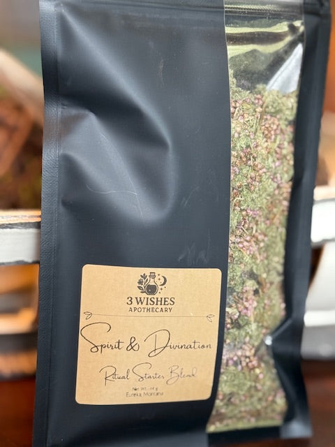 Black coffee bag with a label featuring '3 Wishes Apothecary' on a blurred background showing herbal blend